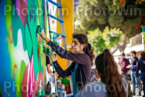 אמן צעיר מצייר ציור קיר תוסס, רקע רחוב עירוני, ממדינת ישראל. שַׂמֵחַ, אמן, אומנות