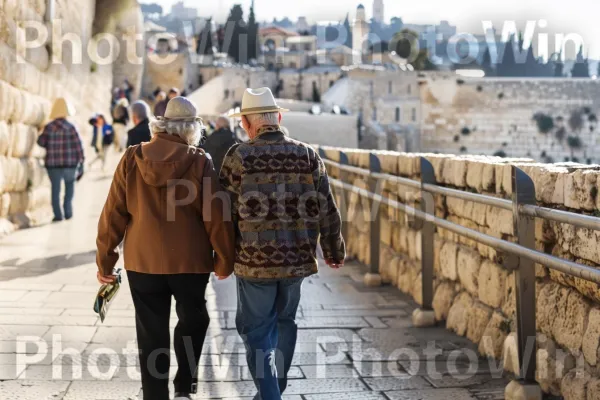 זוג קשישים צועדים יד ביד, מעלים זיכרונות מהרפתקאות העבר, ממדינת ישראל. שָׁמַיִם, בית המקדש, כובע