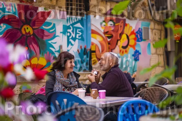 חברים נהנים מקפה ושיחה בבית קפה בירושלים, ממדינת ישראל. רְהִיטִים, כְּחוֹל, צמח