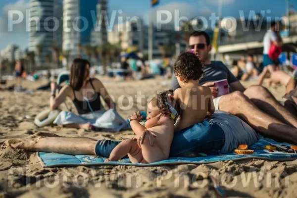 משפחה נהנית מפיקניק בחוף הים בתל אביב, ממדינת ישראל. החוף, צבע תכלת, בגד ים