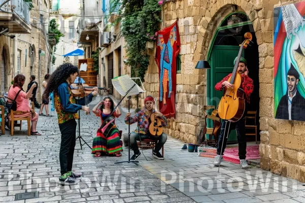 אמני רחוב משעשעים עוברי אורח בעיר העתיקה של יפו, ממדינת ישראל. כלי נגינה, תַשׁתִית, צמח