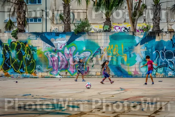 ילדים משחקים כדורגל ברחובות תל אביב, ממדינת ישראל. בִּניָן, צֶבַע, פְּנַאִי