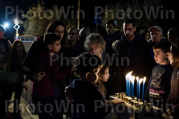 משפחה חוגגת את חנוכה בטקס הדלקת חנוכייה באשקלון, ממדינת ישראל. עֵץ, אֲנָשִׁים, נוֹפֶשׁ