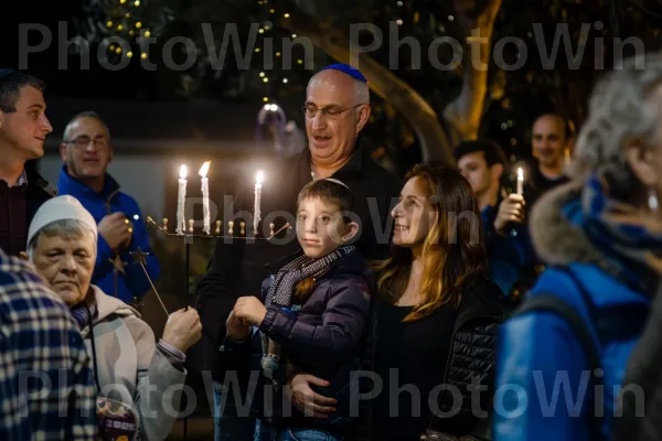 משפחה חוגגת את חנוכה בטקס הדלקת חנוכייה באשקלון, ממדינת ישראל. נר, פְּנַאִי, כֵּיף