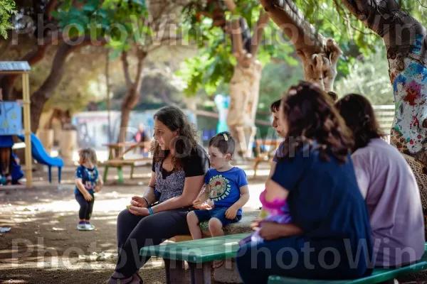 אמהות מפטפטות כשהן צופים בילדיהן משחקים בפארק, ממדינת ישראל. עלה, יונק, שְׁכוּנָה