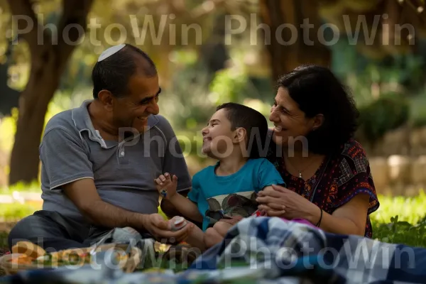 משפחה נהנית מפיקניק בפארק ירושלמי, ממדינת ישראל. שיתוף, שַׂמֵחַ, אנשים בטבע