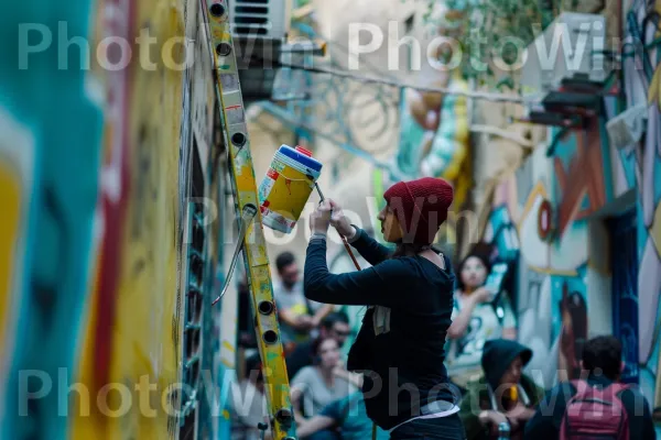 אמן רחוב המצייר ציורי קיר תוססים בירושלים, ממדינת ישראל. פְּנַאִי, חולצה קצרה, נוֹפֶשׁ