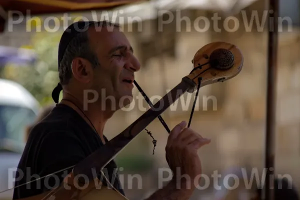 מוזיקאי רחוב מנגן מוזיקה מסורתית בכיכר תוססת, ממדינת ישראל. מוּסִיקָאִי, אביזר גיטרה, מוּסִיקָה