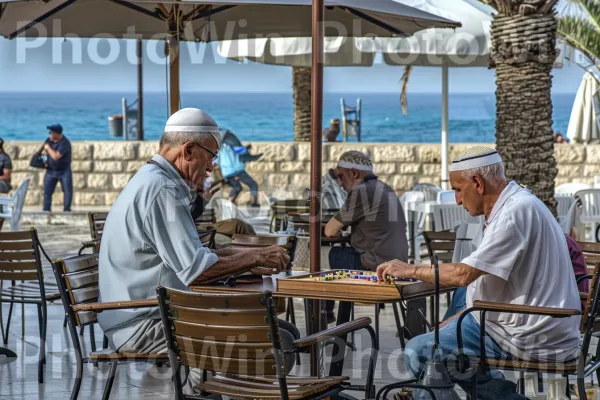 זקנים משחקים שש בש מחוץ לבית קפה ביפו, ממדינת ישראל. שולחן, כובע, ריהוט גן