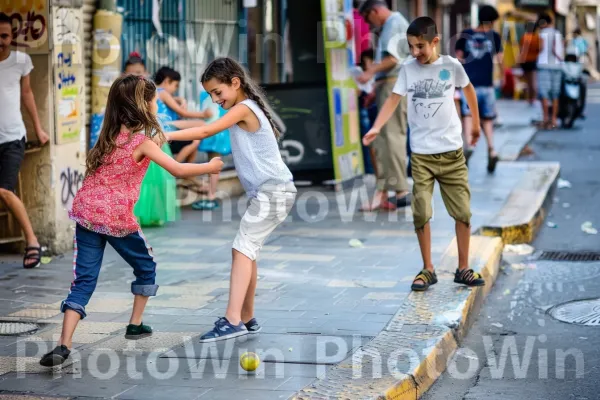 ילדים משחקים ברחובות שכונה תל אביבית תוססת, ממדינת ישראל. מִכְנָסַיִים קְצָרִים, שְׁעוֹת הַיוֹם, עוֹמֵד