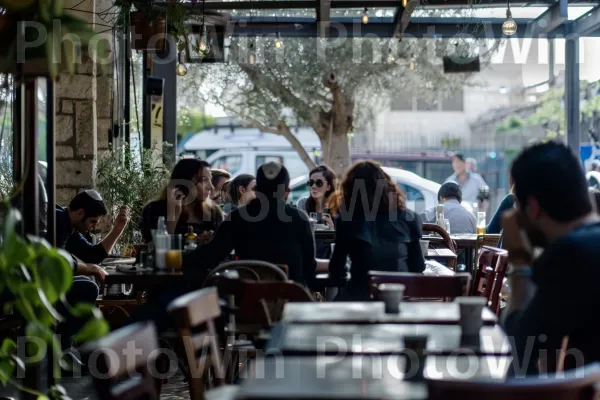 בית קפה שוקק בשכונה האופנתית פלורנטין, מלא פטפוטים, ממדינת ישראל. צמח, כִּסֵא, עֵץ