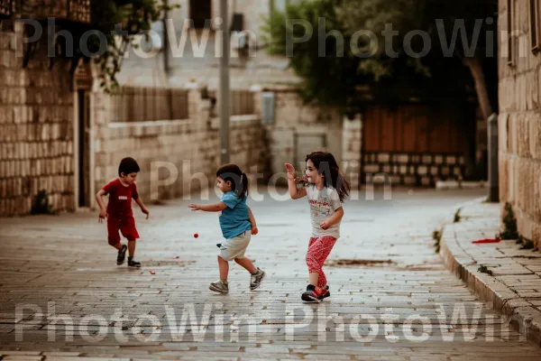 ילדים משחקים ברחובות השכונה ההיסטורית של ירושלים, התמימות בשפע ממדינת ישראל. בַּעֲלֵי הַחוּלִיוֹת, מִכְנָסַיִים קְצָרִים, רַצָפוּת