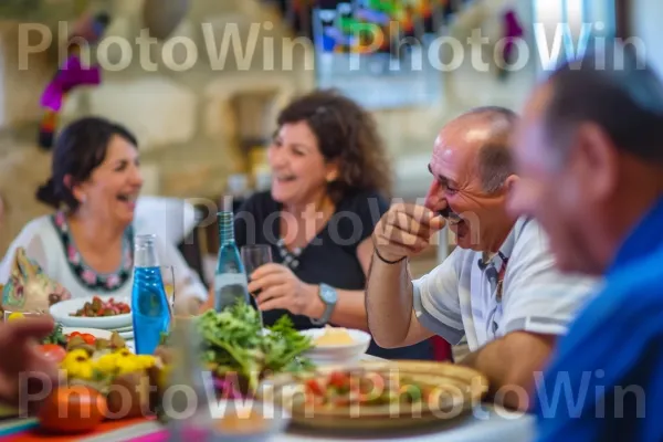 קבוצת חברים צוחקת וחולקת סיפורים בארוחה מסורתית, ממדינת ישראל. מזון, כלי שולחן, שולחן