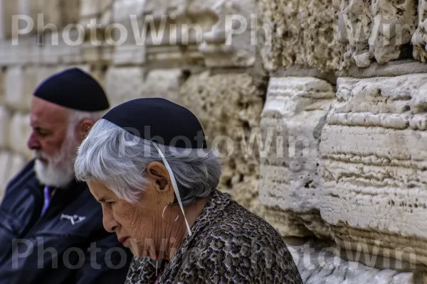 זוג מבוגרים מתפללים בכותל מוצאים נחמה באמונתם, ממדינת ישראל. בית המקדש, אירוע, הִיסטוֹרִיָה