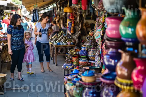 חברים ומשפחות בוחנים שווקים תוססים מלאים בעבודת יד, ממדינת ישראל. מוכר, מַזכֶּרֶת, צרכן