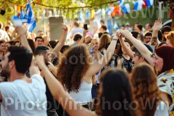 קהל רוקד בחגיגה במהלך פסטיבל עם ישראלי תוסס ממדינת ישראל. צהוב, שַׂמֵחַ, כובע