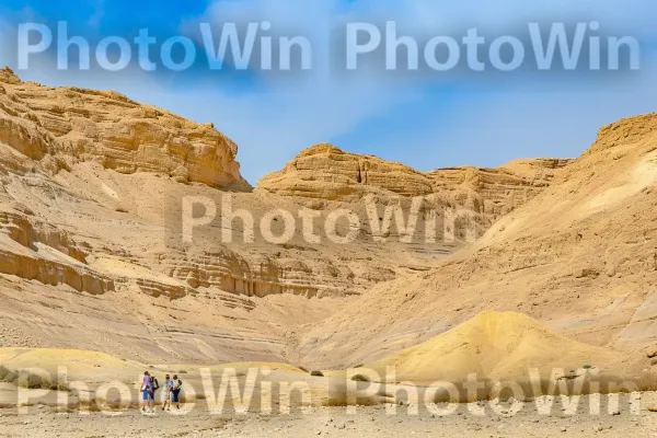 קבוצת חברים מטיילת בנופים היפים של מדבר הנגב, ממדינת ישראל. שָׁמַיִם, סלע יסוד, נוֹף