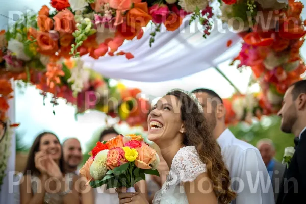 זוג צעיר חוגג את חתונתו מתחת לחופה פרחונית, ממדינת ישראל. הַלבָּשָׁה, חיוך, צמח