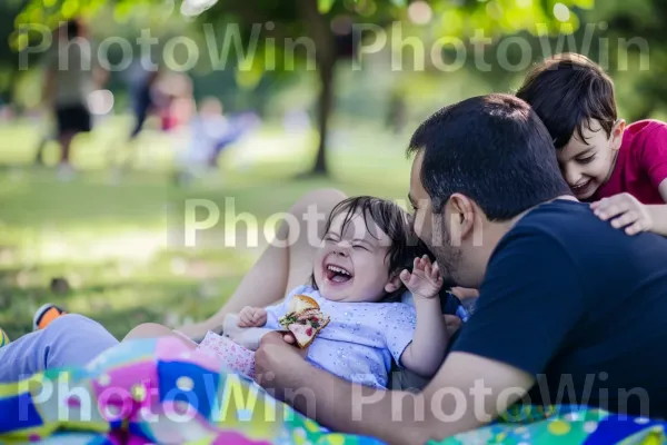 הורים וילדים צוחקים בעודם נהנים מפיקניק בפארק. חיוך, צמח, צהוב