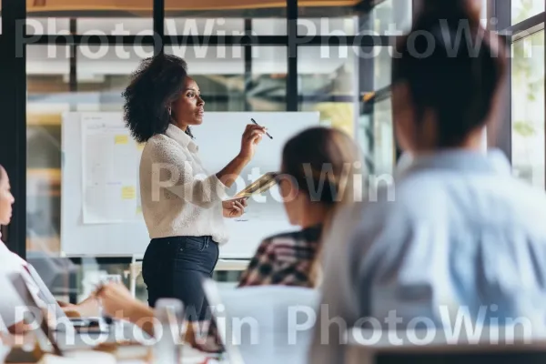 מנהלת אישה מובילה פגישה, מעוררת את הצוות שלה בביטחון. חוּלצָה, כלי שולחן, כִּסֵא